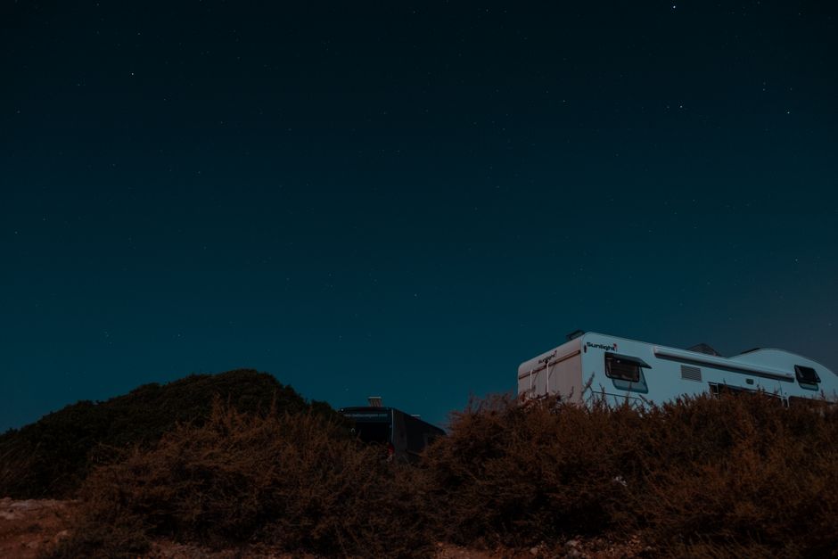 RV camper under a starry night sky in a rural setting, perfect for adventure and tranquility.