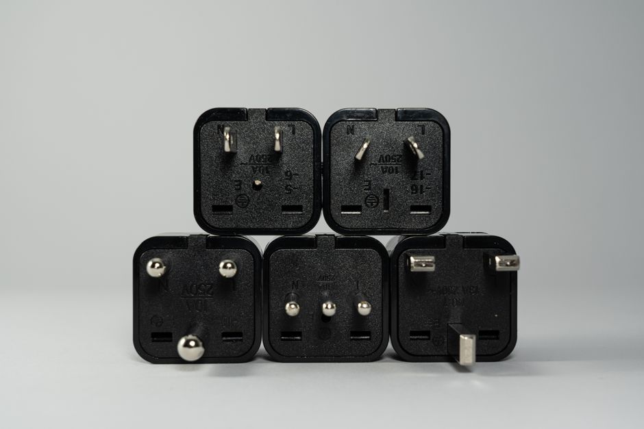 A collection of various black international power plug adapters for global electronics use.