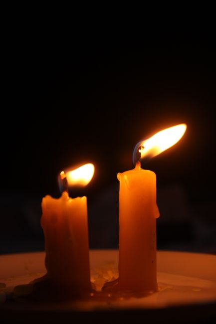 Two burning candles casting a warm glow in the dark, creating a serene and peaceful atmosphere.